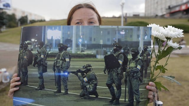 Bei einer Demonstration in Minsk präsentiert eine Frau ein Foto der gegen die Protestbewegung eingesetzten Sicherheitskräfte. Bei einer Demonstration in Minsk präsentiert eine Frau ein Foto der gegen die Protestbewegung eingesetzten Sicherheitskräfte.