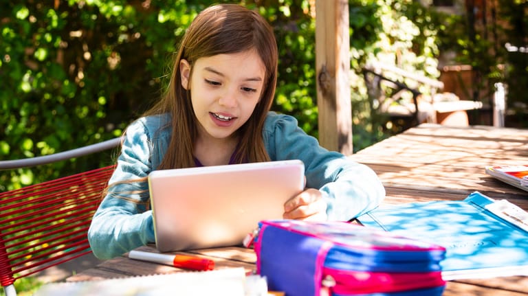 Ein Mädchen lernt mit einem Tablet: Die Telekom will den Heimunterricht mit einer Datenflatrate für Schüler unterstützen.