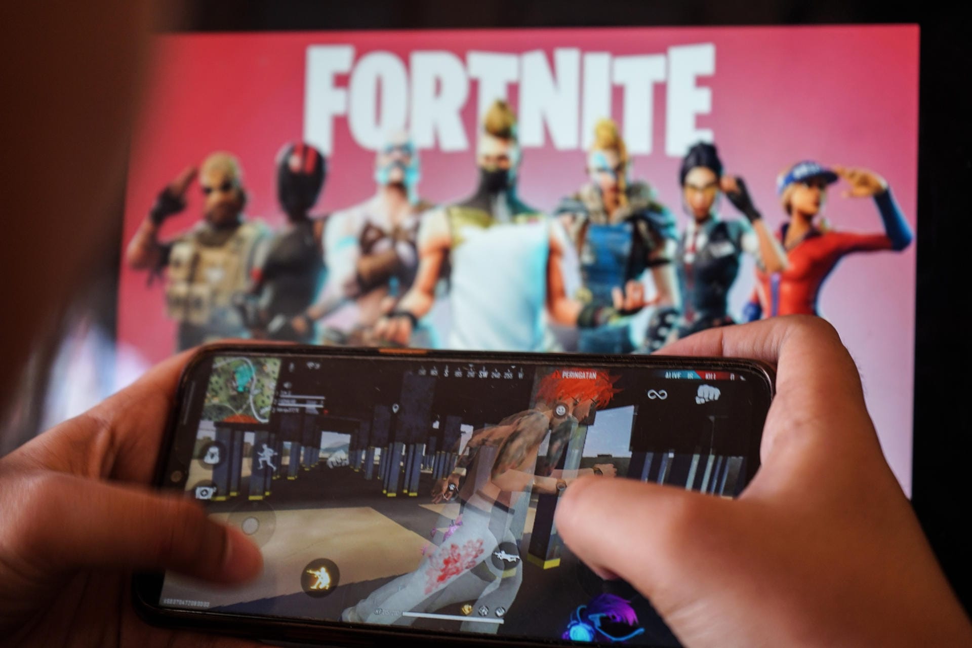 Ein Smartphone mit "Fortnite"-Schriftzug im Hintergrund (Symbolbild): Microsoft mischt sich in den Streit zwischen Apple und den "Fortnite"-Machern ein.