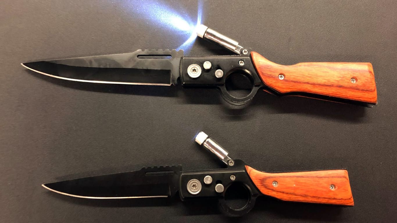 Zwei Springmesser, deren Form an Schusswaffen erinnert, liegen auf einem Tisch: Diese verbotenen Gegenstände wollte ein Mann am Flughafen Düsseldorf ins Land schmuggeln.