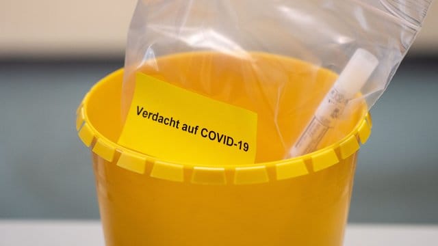 Ein Teströhrchen liegt in einer Tüte mit der Aufschrift "Verdacht auf COVID-19".