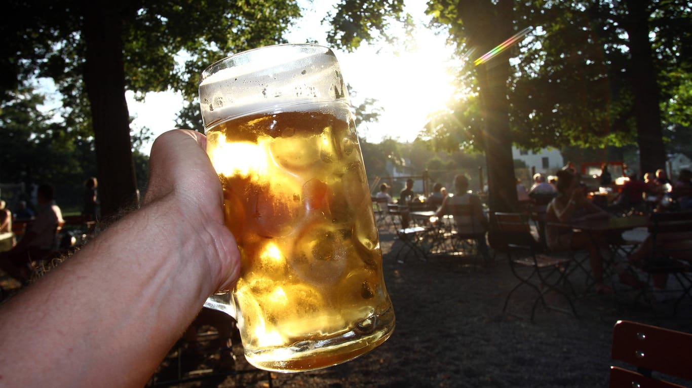 Eine Hand hält eine Maß Bier in München in die Abendsonne: Wegen steigender Corona-Zahlen hat die Stadt eine Regelung für ein geplantes Alkoholverbot beschlossen.
