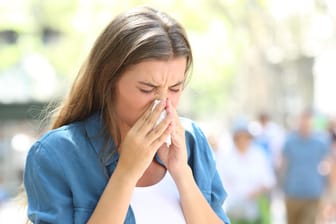 Eine Frau putzt sich die Nase: Eine Sommergrippe ist lästig. Doch einfache Hausmittel können helfen, die Beschwerden zu lindern.