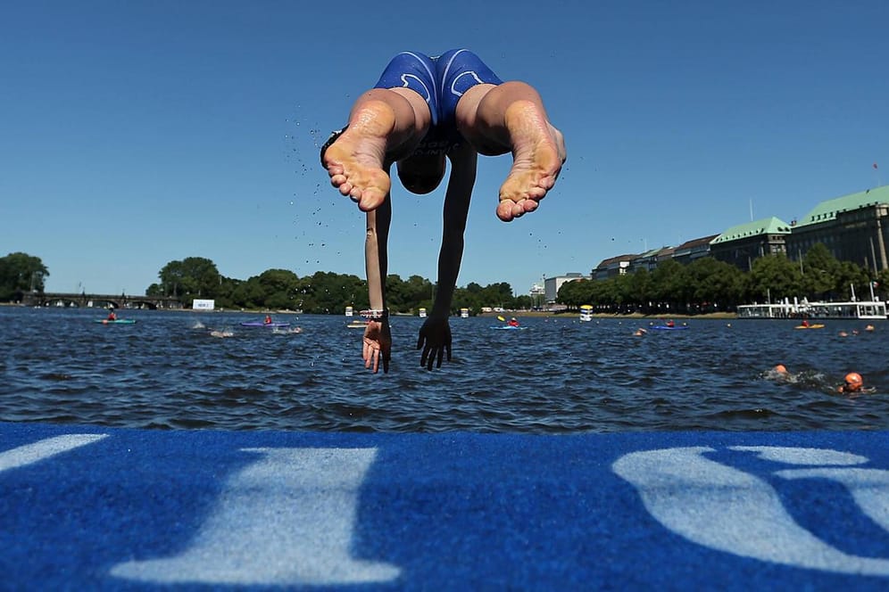 Ein Teilnehmer springt ins Wasser (Archivbild): In Hamburg soll der Traithlon trotz Corona stattfinden.