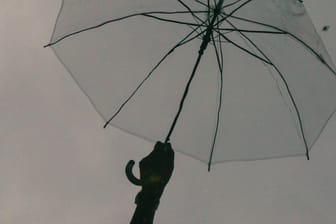 Ein Regenschirm vor einem grauen Himmel (Symbolbild): In Dortmund wird es stürmisch.