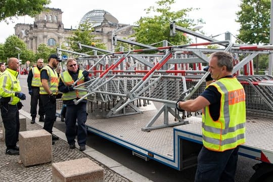 Polizisten verteilen im Berliner Regierungsviertel, wie hier vor dem Reichstagsgebäude, Absperrgitter, weil die Stadt trotz des Demonstrationsverbots mit Protesten rechnet.
