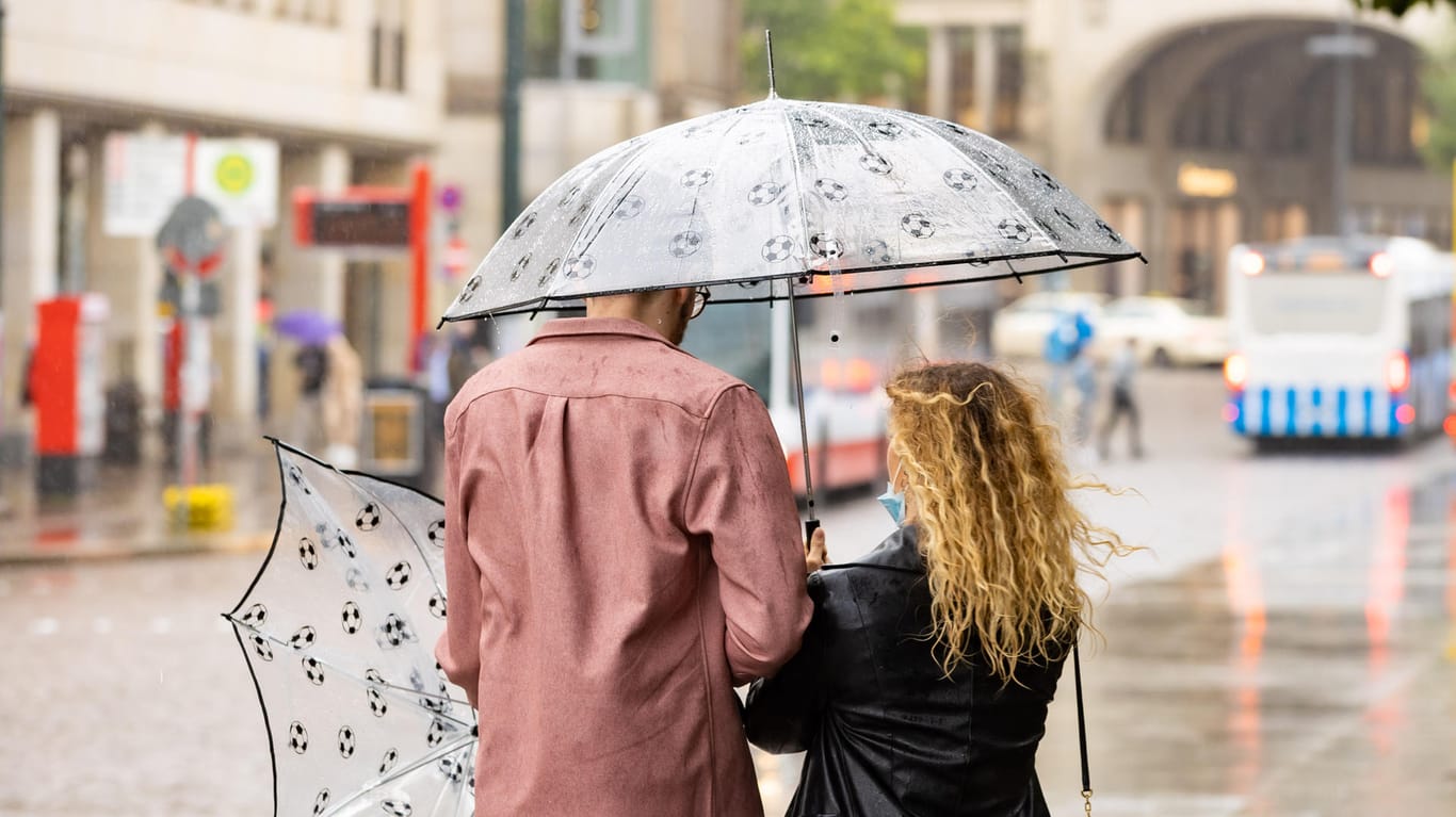 Mit Regenschirmen schützt sich ein Paar vor dem Regenwetter: Auch in den kommenden Tagen bleibt das Wetter in Norddeutschland unbeständig.