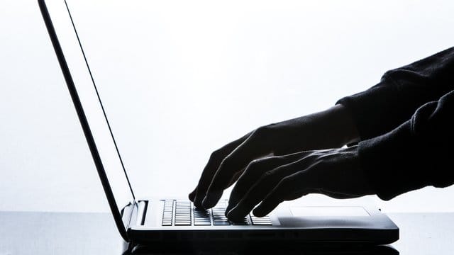 Ein Mann tippt auf einer Tastatur eines Laptops. Ein Mann tippt auf einer Tastatur eines Laptops.