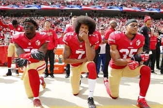 Colin Kaepernick (M), Eli Harold (l) und Eric Reid von den San Francisco 49ers knien 2016 beim Abspielen der US-Nationalhymne.