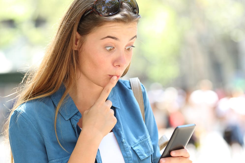 Eine Frau erschrickt beim Blick auf ihr Smartphone: Wir erklären, wie Sie peinliche WhatsApp-Nachrichten nachträglich löschen können.