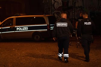 Ein Polizist und ein Gerichtsmediziner gehen zu einem Einsatzfahrzeug der Polizei im Monbijoupark in Berlin-Mitte (Archivbild): Ein Begleiter des Jugendlichen wurde erheblich verletzt.