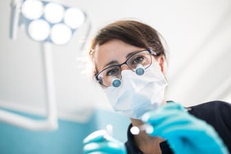 Eine Zahnärztin bei der Behandlung (Archivbild): Schon ein einziges Zahnimplantat mit Krone kann schnell mehr als 2.000 Euro kosten.