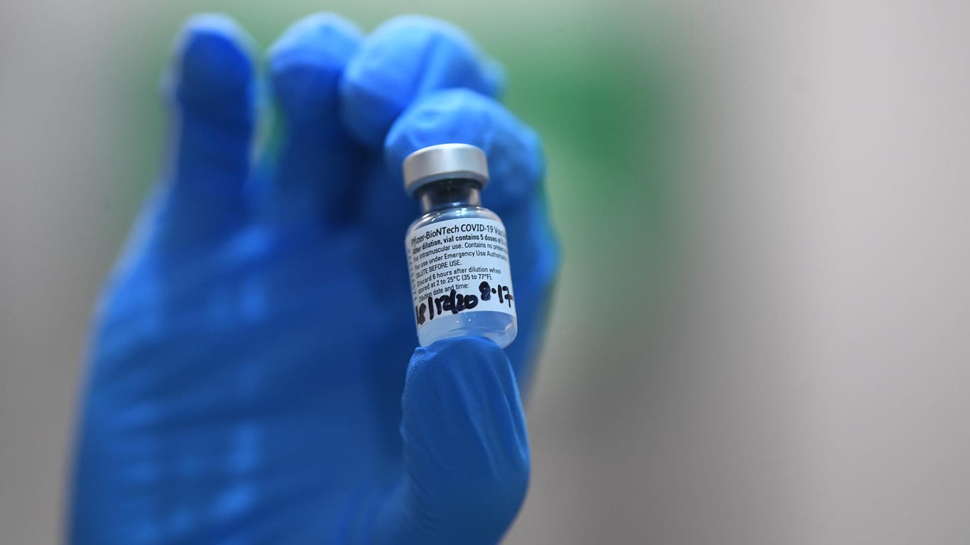 Eine Hand hält eine Ampulle mit dem Biontech-Impfstoff: Großbritannien will den Impfstoff notfalls einfliegen lassen.