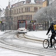 Verschneite Straßenszene: Ein Radfahrer am Erfurter Fischmarkt beim ersten Schnee des Jahres 2021 am 3. Januar.
