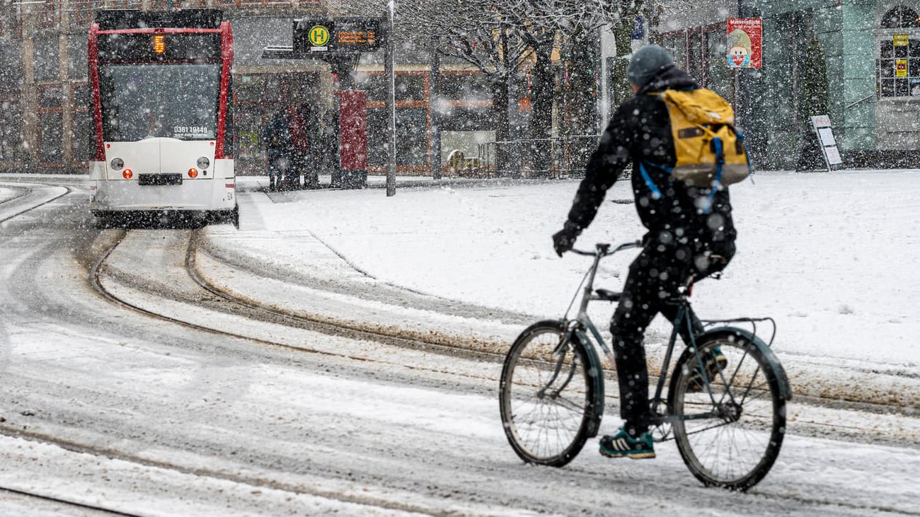 Verschneite Straßenszene: Ein Radfahrer am Erfurter Fischmarkt beim ersten Schnee des Jahres 2021 am 3. Januar.