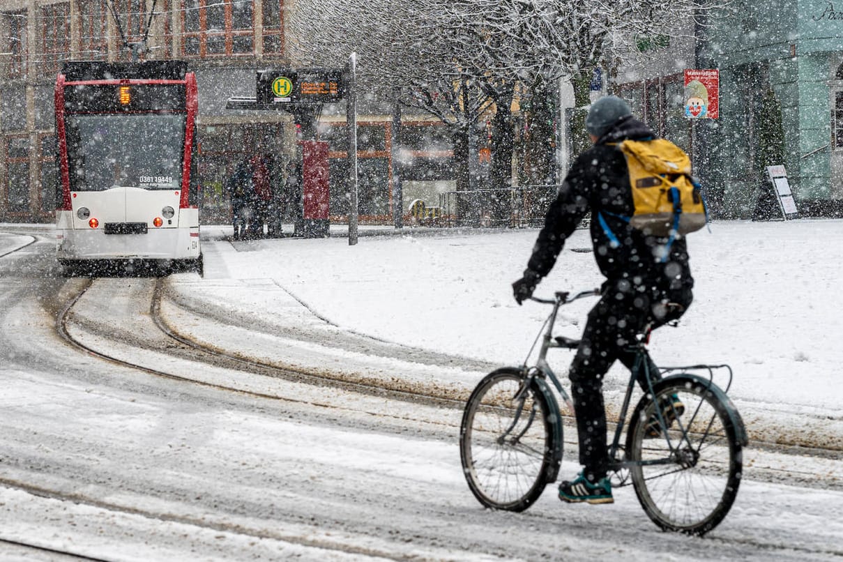 Verschneite Straßenszene: Ein Radfahrer am Erfurter Fischmarkt beim ersten Schnee des Jahres 2021 am 3. Januar.