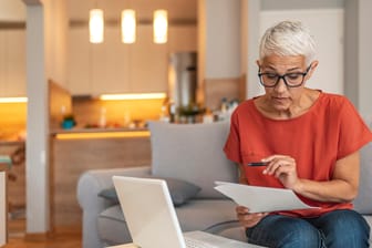 Eine ältere Frau prüft Dokumente (Symbolbild): Die Riester-Rente kann ein Baustein der privaten Altersvorsorge sein.