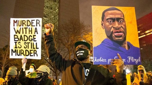 Ein Mann hält während einer Demonstration gegen Polizeigewalt Minneapolis ein Portrait von George Floyd in die Höhe.