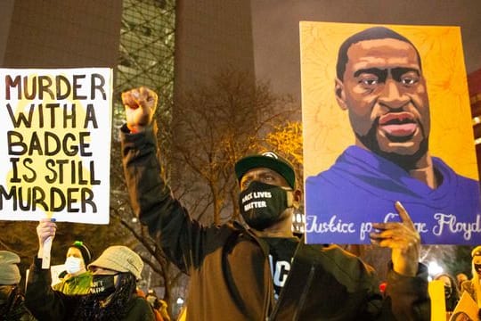 Ein Mann hält während einer Demonstration gegen Polizeigewalt Minneapolis ein Portrait von George Floyd in die Höhe.