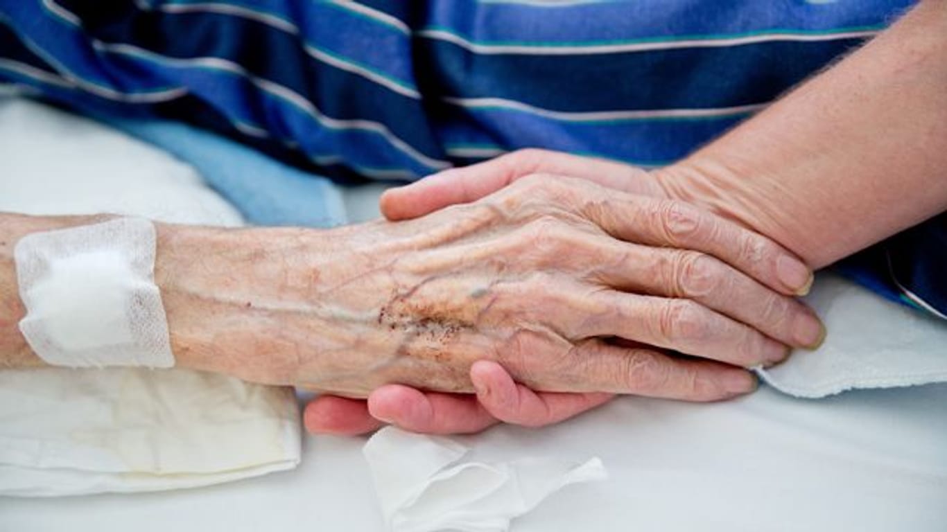 Eine Krankenpflegerin der Onkologie im Klinikum in Nürnberg hält die Hand eines Patienten.