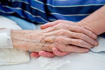 Eine Krankenpflegerin der Onkologie im Klinikum in Nürnberg hält die Hand eines Patienten.