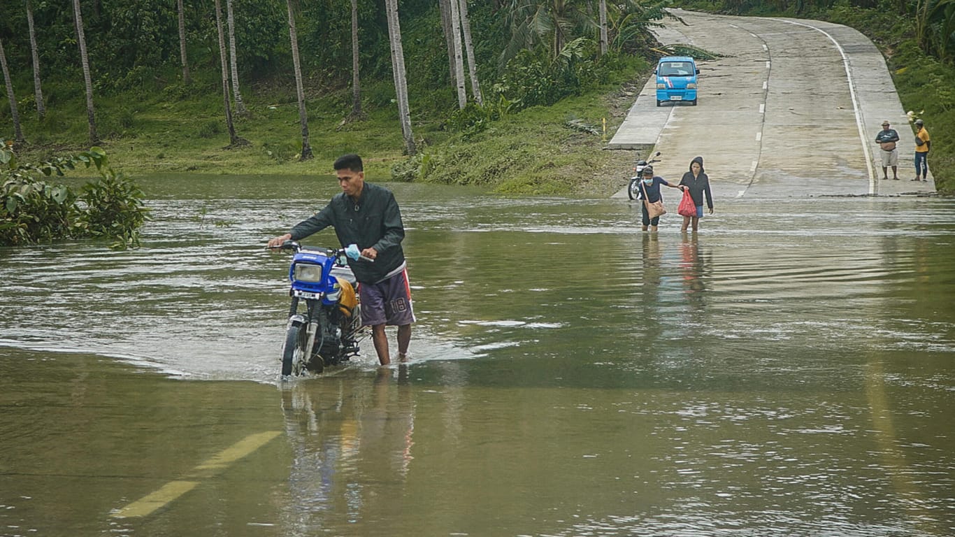 Bewohner des Küstenortes Arteche überqueren eine überflutete Straße: Der Taifun "Surigae" hat zu einer Evakuierung von mehr als 100.000 Menschen aus mehreren Dörfern geführt.