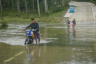 Bewohner des Küstenortes Arteche überqueren eine überflutete Straße: Der Taifun "Surigae" hat zu einer Evakuierung von mehr als 100.000 Menschen aus mehreren Dörfern geführt.