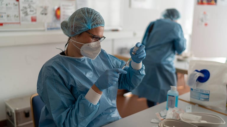 Mitarbeiterin eines Krankenhauses zieht Impfstoff aus einem Behältnis: Die Impfkampagne müsse jetzt angepasst werden, fordert der Marburger Bund.