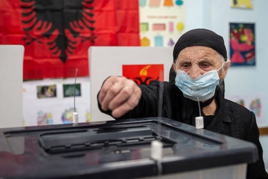 Eine Frau wirft in Tirana ihren Stimmzettel in eine Wahlurne.