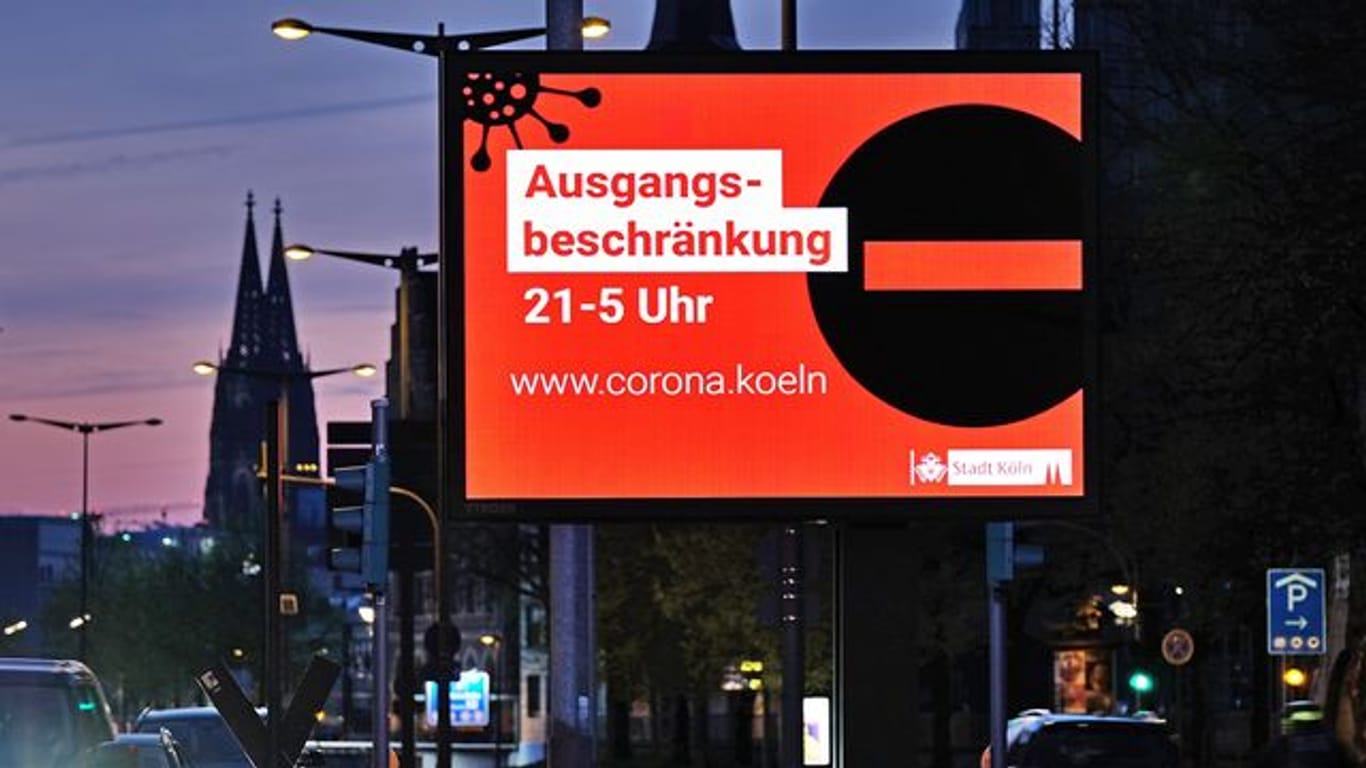 Auf einer Anzeigetafel in Köln wird auf die Ausgangsbeschränkung hingewiesen.