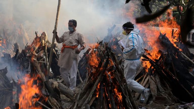 Neu-Delhi: Angehörige neben brennenden Scheiterhaufen von Opfern, die an den Folgen einer Corona-Infektion gestorben sind.