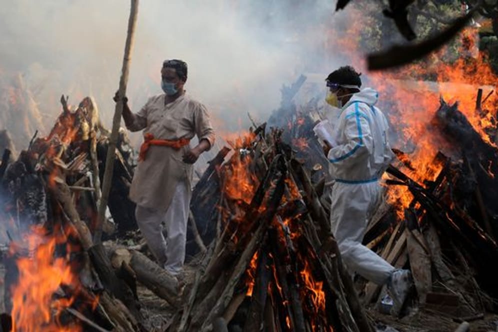 Neu-Delhi: Angehörige neben brennenden Scheiterhaufen von Opfern, die an den Folgen einer Corona-Infektion gestorben sind.
