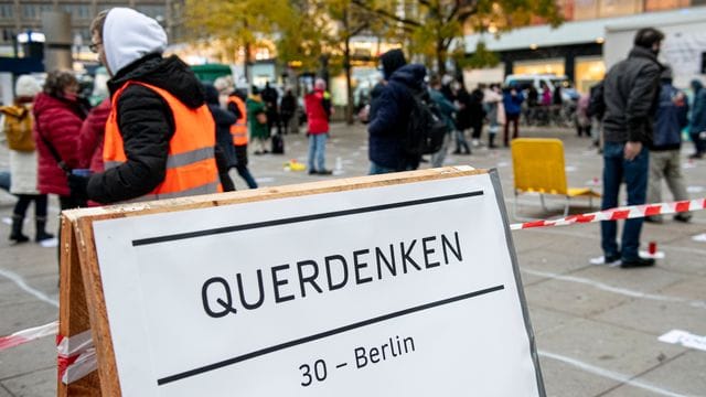 Teilnehmer stehen auf bei einer "Querdenker"-Demo gegen die Corona-Einschränkungen auf dem Alexanderplatz in Berlin (Archiv). Teilnehmer stehen auf bei einer "Querdenker"-Demo gegen die Corona-Einschränkungen auf dem Alexanderplatz in Berlin (Archiv).