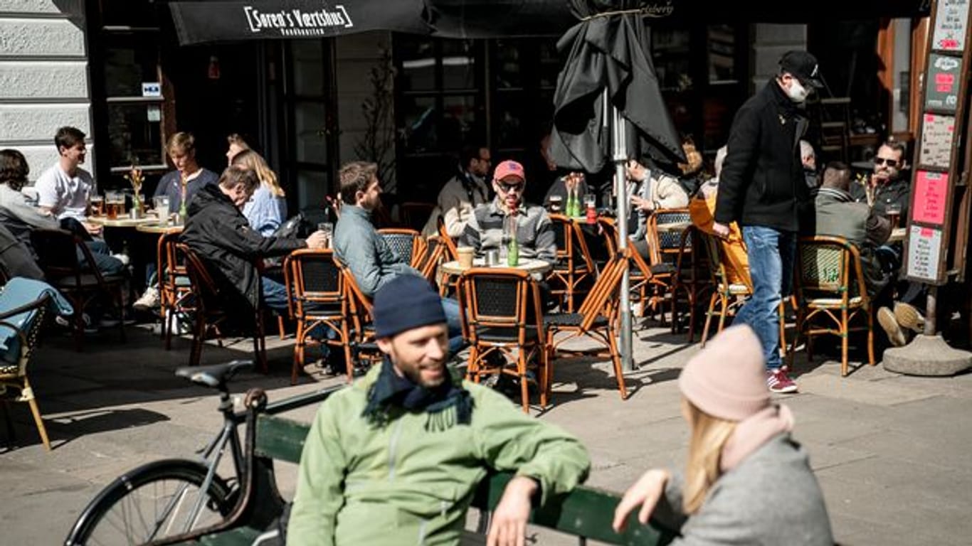 Menschen sitzen im belebten Außenbereich eines Cafés in der dänischen Haupstadt Kopenhagen.
