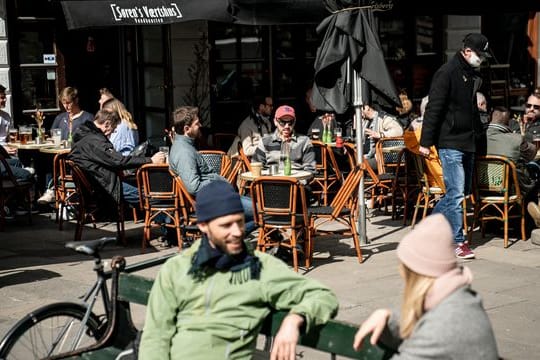 Menschen sitzen im belebten Außenbereich eines Cafés in der dänischen Haupstadt Kopenhagen.