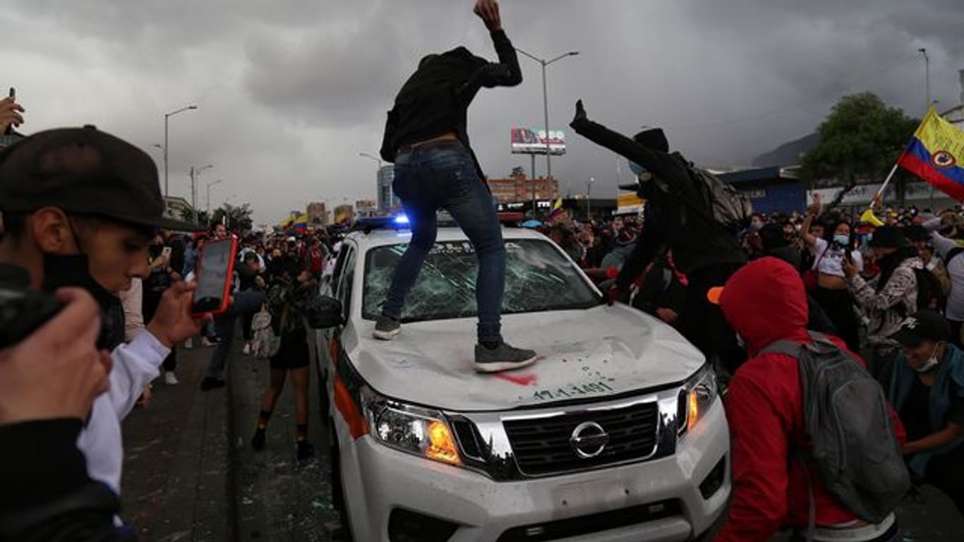 Demonstranten schlagen während des Protests in Bogota auf einen Polizeiwagen ein.