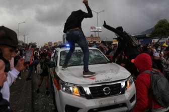 Demonstranten schlagen während des Protests in Bogota auf einen Polizeiwagen ein.
