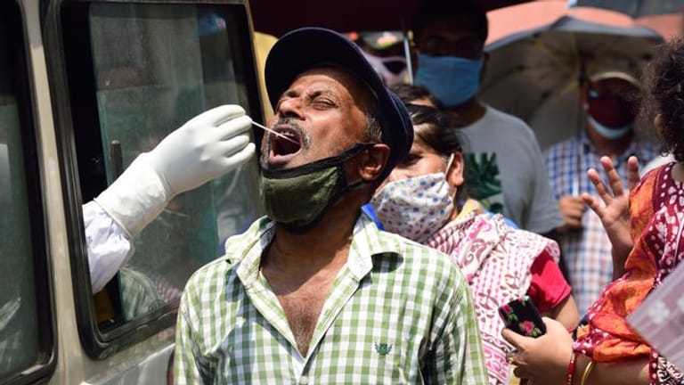 Ein Mitarbeiter des Gesundheitswesens entnimmt in Kalkutta aus einem Auto heraus einen Abstrich für einen Corona-Test.