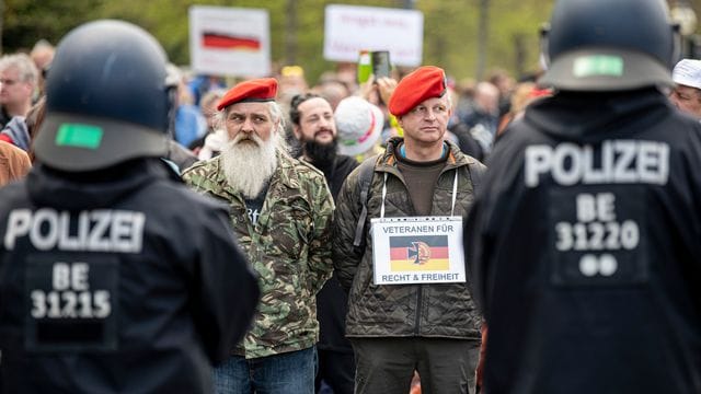 Zwei Demonstranten stehen mit einem Schild - "Veteranen für Recht und Freiheit" - auf der Straße des 17.