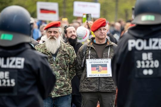 Zwei Demonstranten stehen mit einem Schild - "Veteranen für Recht und Freiheit" - auf der Straße des 17.