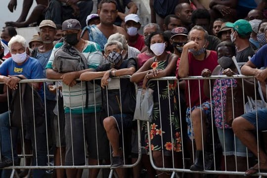Menschen warten in Rio de Janeiro in einer Schlange auf eine kostenlose Mahlzeit.