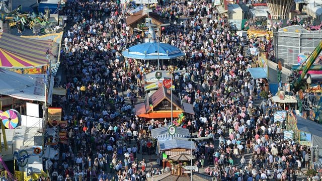Zahlreiche Menschen gehen bei Sonnenschein über das Oktoberfest-Gelände in München. Zahlreiche Menschen gehen bei Sonnenschein über das Oktoberfest-Gelände in München.