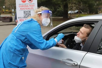 Eine Ärztin an einem Drive-In-Testzentrum in Neu-Isenburg nimmt eine Probe von einem Autofahrer. In den vergangenen Tagen ist die Zahl der Neuinfektionen zurückgegangen.