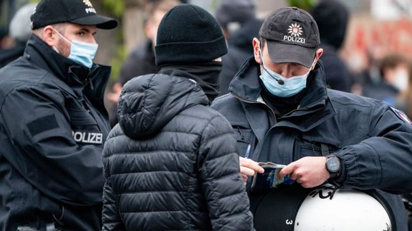 Polizisten kontrollieren die Personalien von einem Teilnehmer einer Demonstration in Hamburg.