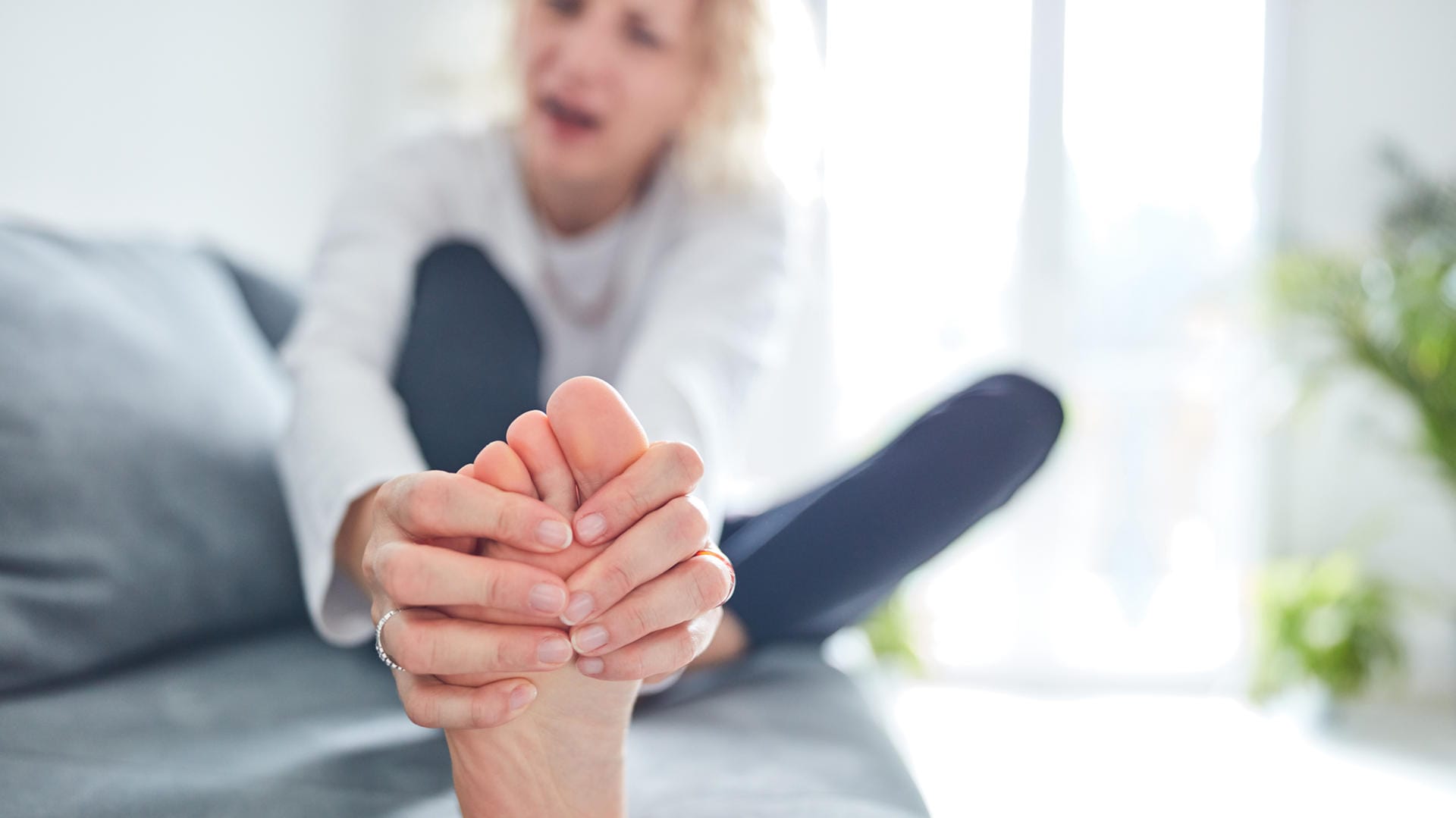 Eine Frau betrachtet ihren Fuß: Nagelpilz ist zwar meist harmlos, sieht aber unschön aus.