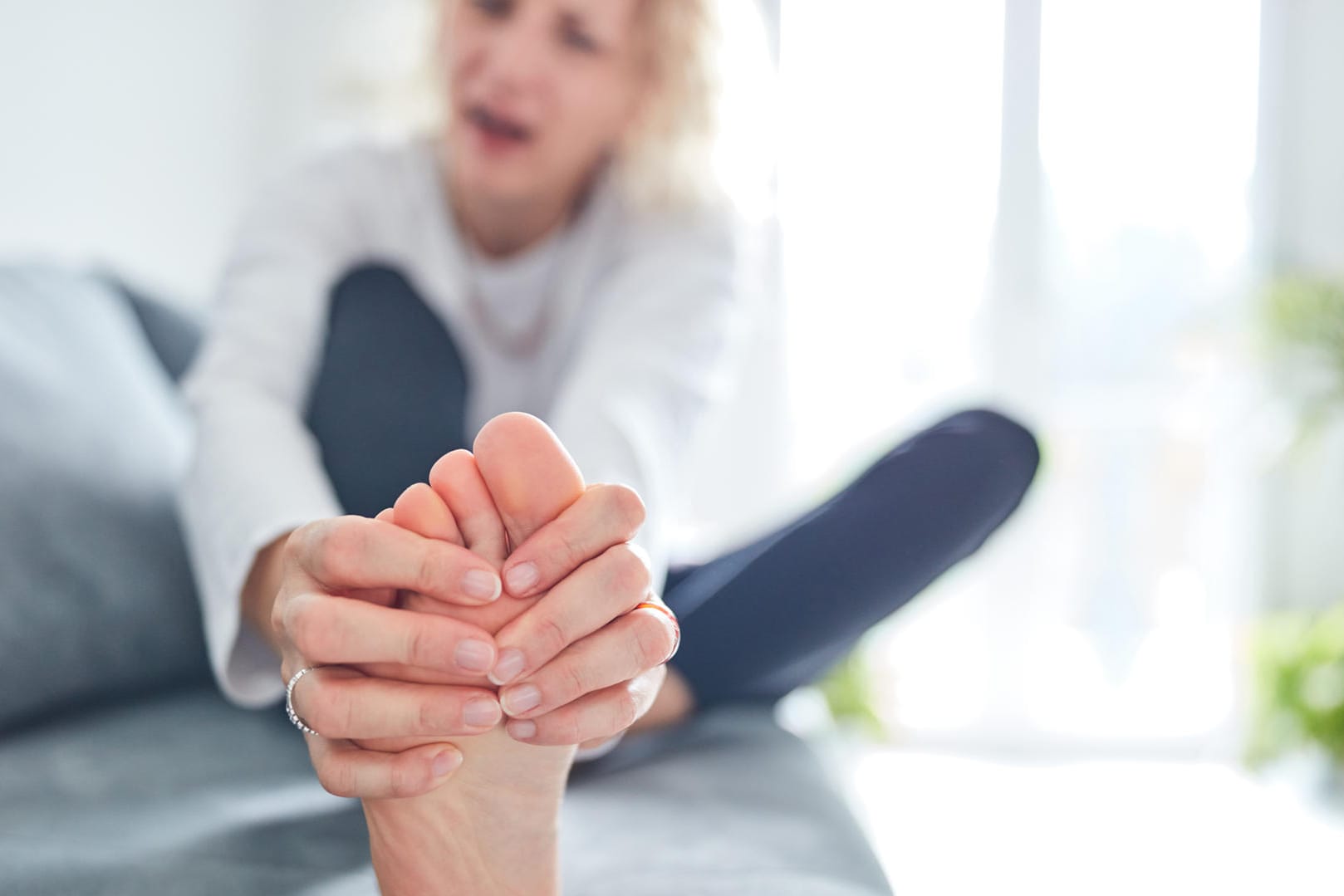 Eine Frau betrachtet ihren Fuß: Nagelpilz ist zwar meist harmlos, sieht aber unschön aus.