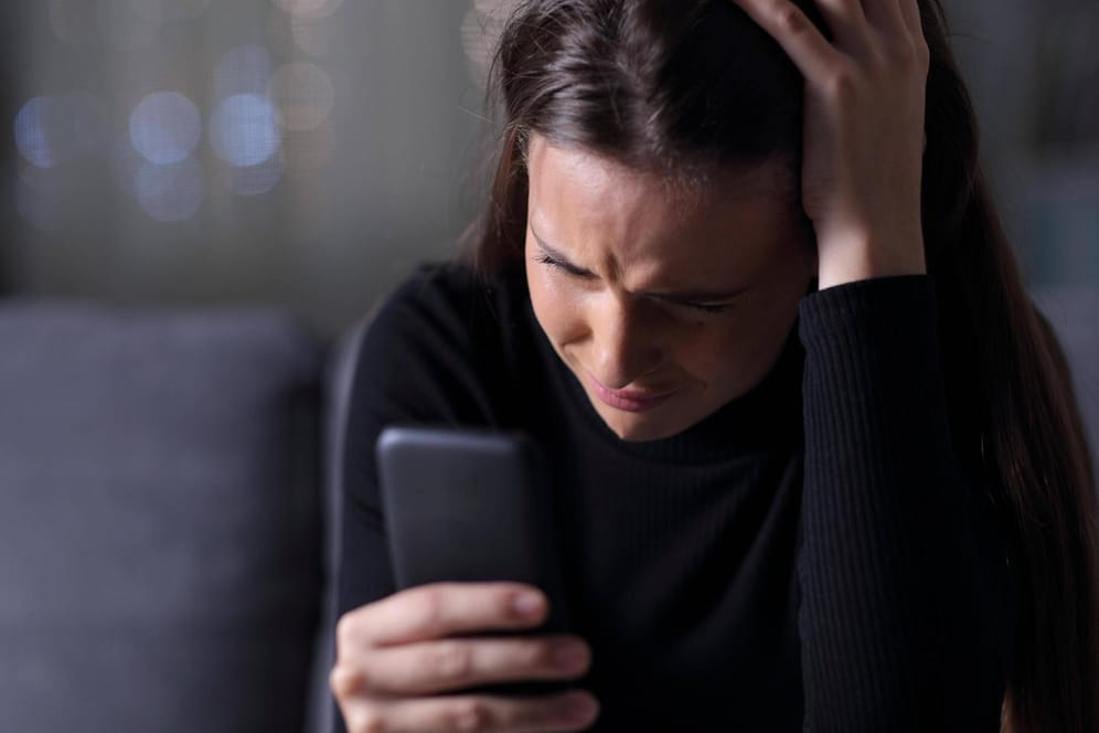 Eine Jugendliche schaut traurig auf ihr Smartphone (Symbolbild): Die Polizei ermittelt wegen zahlreicher Straftaten in Online-Chats.