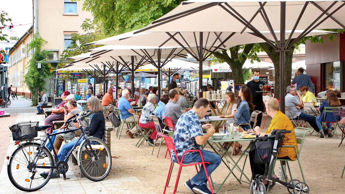 Menschen sitzen in einem Café in Karlsruhe (Archivbild): Sollte die Inzidenz unter 100 bleiben, stehen Lockerungen an.