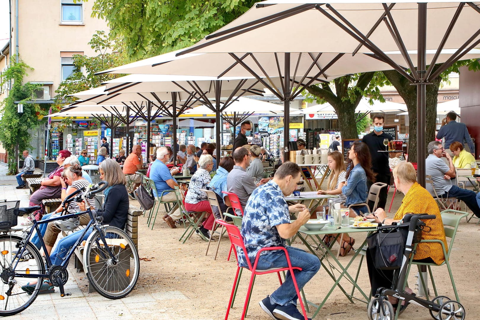 Menschen sitzen in einem Café in Karlsruhe (Archivbild): Sollte die Inzidenz unter 100 bleiben, stehen Lockerungen an.