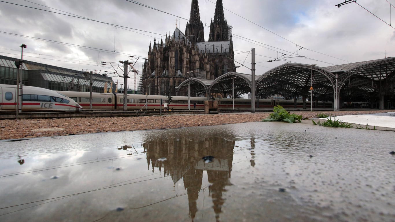 Blick auf den Kölner Hauptbahnhof und den Dom hinter einer Regenpfütze (Symbolbild): Das trübe Wetter hält an, auch das Pfingstwochenende wird alles andere als frühlingshaft.